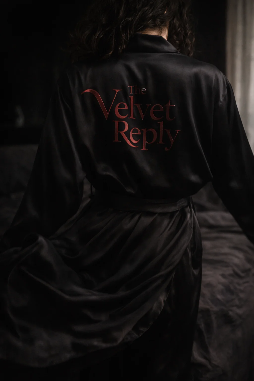 Black satin robe with The Velvet Reply burgundy serif print on the back